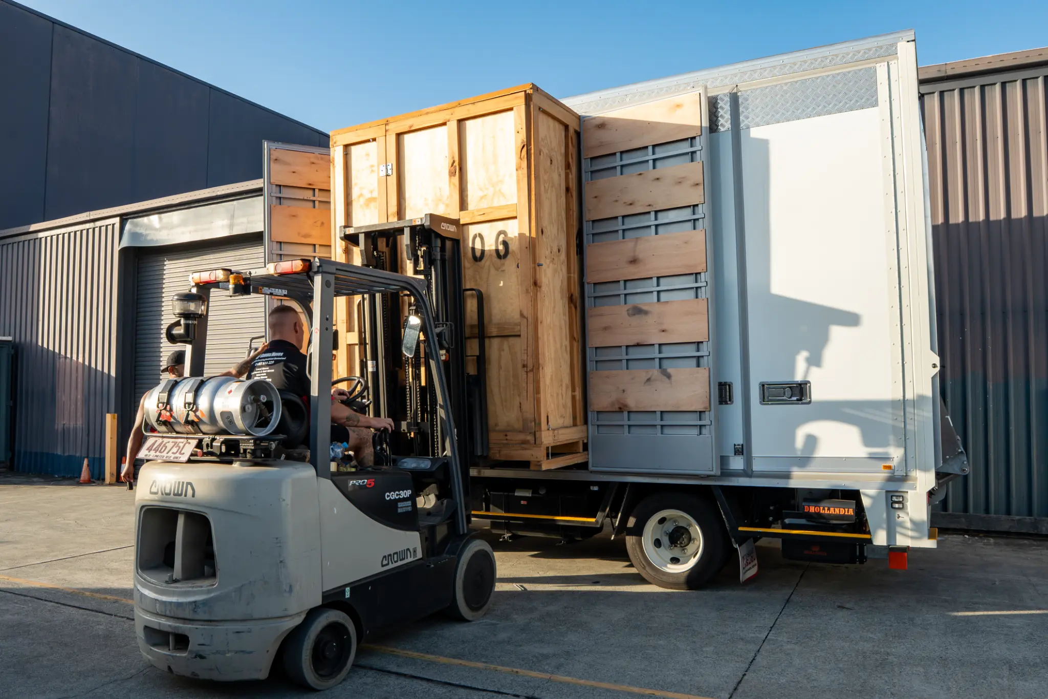A forklift loading a timber storage module into a truck